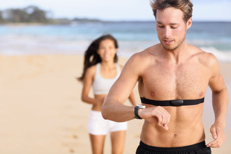 couple running on beach checking heart monitor