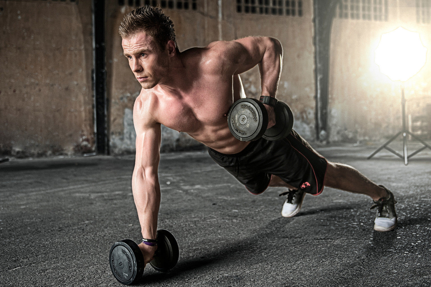 man exercising with weights in push up position