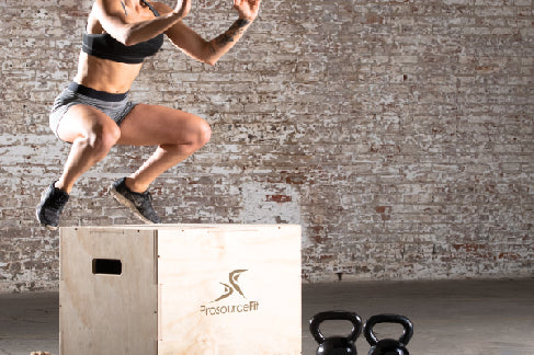 fit woman jumping on prosourcefit plyometric jump box with prosourcefit kettlebells on the ground