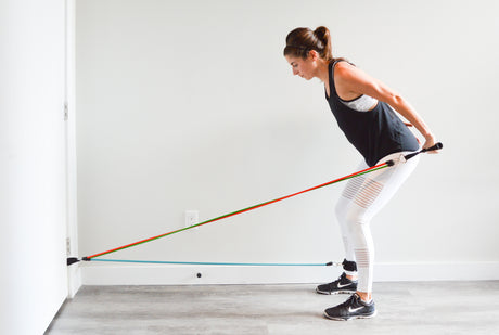 woman working out arm and leg with anchored resistance bands